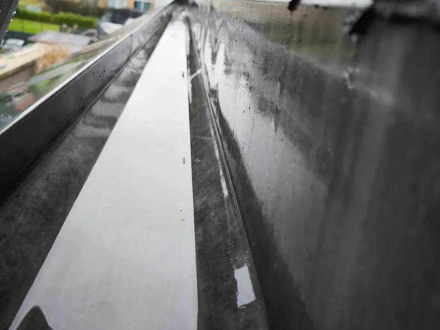 Chéneau nettoyé où l'eau s'écoule à nouveau librement vers la descente